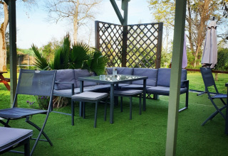 Gemütliche Sitzgruppe auf grüner Terrasse im Freien bei Camping d'Artagnan, Occitanie, Frankreich.