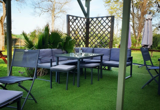 Outdoor lounge with grey patio furniture and a pergola at Camping d'Artagnan holiday park in Occitanie, France.