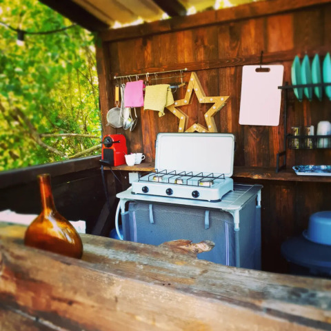 Outdoor-Küche mit Gasherd, Tassen, Geschirr und Kaffeemaschine im Camping d'Artagnan, Occitanie, Frankreich.