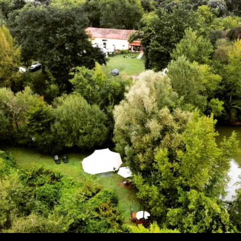 Vista aerea del Camping d'Artagnan in Occitania, Francia, con tende, vegetazione rigogliosa e una casa.
