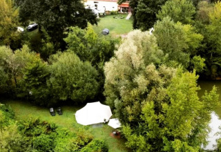 Vista aerea del Camping d'Artagnan in Occitania, Francia, con tende, vegetazione rigogliosa e una casa.