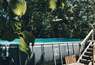 Piscina esterna fuori terra e terrazza in legno circondate da alberi al Camping d'Artagnan in Occitania.
