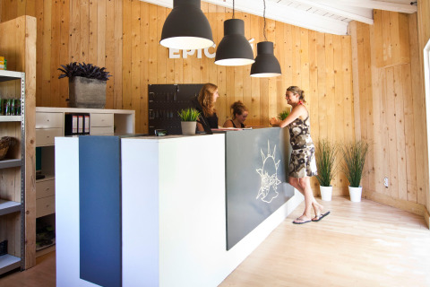 Reception med trævægge på Slow Village Provence Occitane, Occitanie, Frankrig, med gæst og personale.