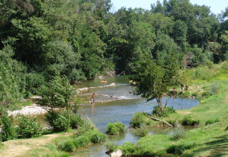 Mensen ontspannen aan de rivier in Slow Village Provence Occitane, een vakantiepark in Occitanië, Frankrijk.
