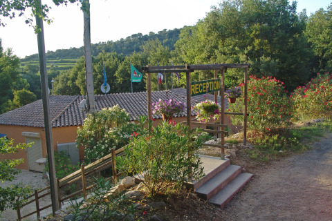 Receptie van Slow Village Provence Occitane vakantiepark, omgeven door bloemen en bomen in Occitanië, Frankrijk.