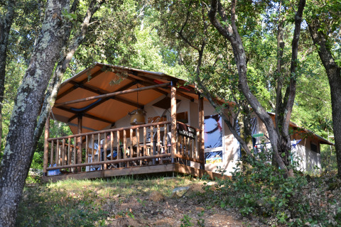 Tienda safari sobre terraza de madera entre árboles en Slow Village Provence Occitane, Occitanie, Francia.