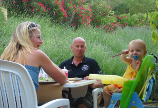 Gezin geniet van een maaltijd in de tuin bij Slow Village Provence Occitane, vakantiedorp in Occitanië, Frankrijk.
