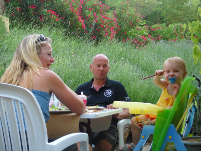 Family enjoys an outdoor meal surrounded by lush greenery at Slow Village Provence Occitane, Occitanie, France.