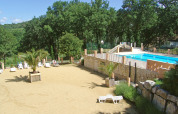 En solrig udendørs pool og sandområde omgivet af grønne træer i Slow Village Provence Occitane, Occitanie.
