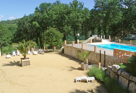 Zonnig zwembad en zandstrand bij Slow Village Provence Occitane vakantiepark in Occitanie, Frankrijk.