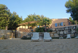 Strandstoelen op zand voor een stenen muur en vakantiewoningen bij Slow Village Provence Occitane, Occitanië, Frankrijk.