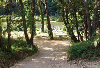 Sentiero tra gli alberi verso una spiaggia sul fiume con persone, Slow Village Provence Occitane, Occitania, Francia.