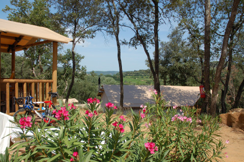 Zicht op Slow Village Provence Occitane in Occitanië, Frankrijk, met bloemen, tenten en een bosrijke omgeving.