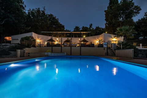 Verlicht zwembad in de avond voor het hoofdgebouw van Slow Village Provence Occitane in Occitanie, Frankrijk.
