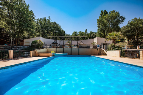 Swimming pool at Slow Village Provence Occitane holiday park, surrounded by trees on a sunny day in Occitanie.