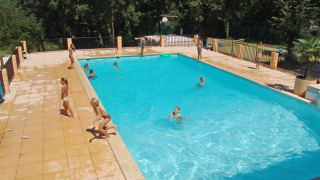 Niños jugando en una piscina exterior rodeada de árboles en Slow Village Provence Occitane, Occitanie.