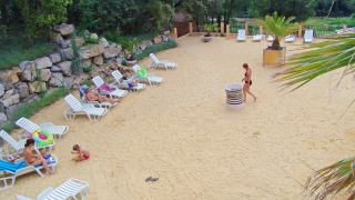 Zona de arena clara con hamacas y visitantes descansando en Slow Village Provence Occitane, Occitania, Francia.