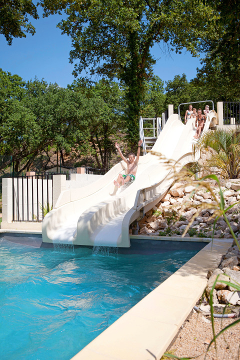 Kinderen glijden van de waterglijbaan bij Slow Village Provence Occitane, vakantiepark in Occitanië, Frankrijk.