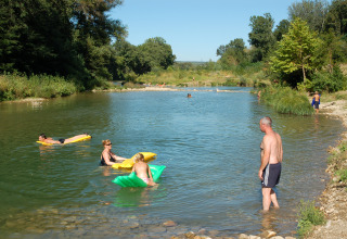 Persone si rilassano e nuotano in un fiume al parco vacanze Slow Village Provence Occitane in Occitania, Francia.