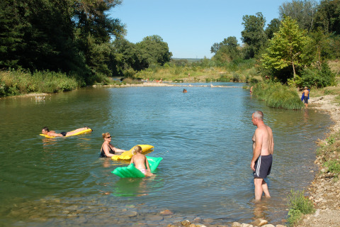 Folk nyder en solrig dag med afslappende badning og svømning i en flod ved Slow Village Provence Occitane.