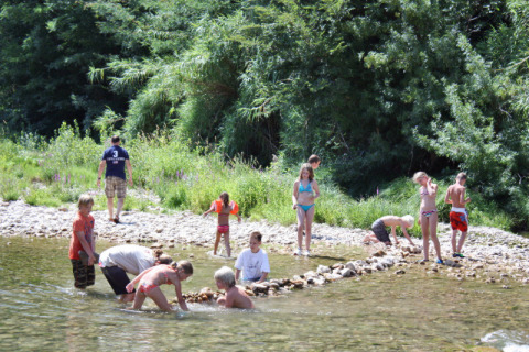 Kinderen spelen in een ondiepe rivier aan het Slow Village Provence Occitane vakantiepark in Occitanië, Frankrijk.