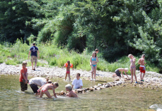Kinderen spelen in een ondiepe rivier aan het Slow Village Provence Occitane vakantiepark in Occitanië, Frankrijk.