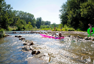 Bambini giocano con gonfiabili in un fiume poco profondo a Slow Village Provence Occitane, Occitania, Francia.