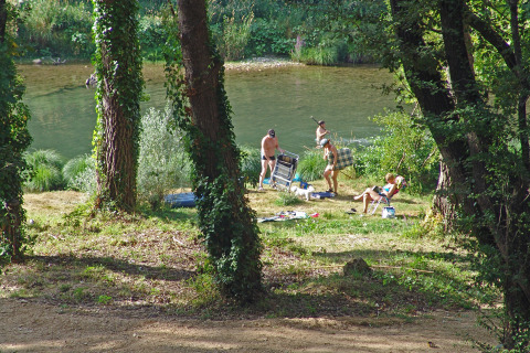 Personas descansan junto al río en Slow Village Provence Occitane, un parque vacacional en Occitania, Francia.