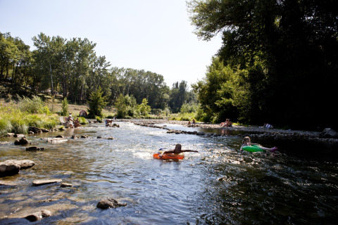Personas se relajan y flotan en flotadores por un río poco profundo en Slow Village Provence Occitane, Francia.