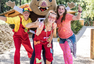 Fire glade mennesker og en maskot poserer udendørs i farverige kostumer på Slow Village Provence Occitane.