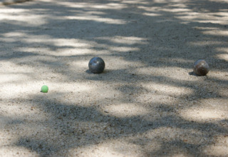 Bocce da petanque e un pallino verde su un campo sabbioso ombreggiato a Slow Village Provence Occitane.