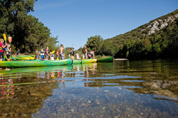 Guests at Slow Village Provence Occitane paddling in canoes on a sunny river in Occitanie, France holiday park.