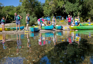 Persone con giubbotti di salvataggio si radunano vicino ai kayak sul lago a Slow Village Provence Occitane, Occitanie, Francia.