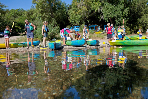 Persone con giubbotti di salvataggio si radunano vicino ai kayak sul lago a Slow Village Provence Occitane, Occitanie, Francia.