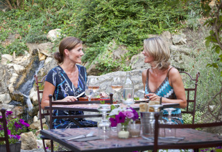 Twee vrouwen genieten samen van een maaltijd buiten aan een tuintafel in Slow Village Provence Occitane, Occitanië.