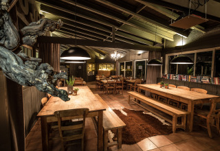 Gezellige eetplek met houten tafels, banken, grote lampen en boeken in Slow Village Provence Occitane, Frankrijk.