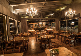 Gezellig restaurant met houten tafels en kroonluchters in Slow Village Provence Occitane, Occitanië, Frankrijk.