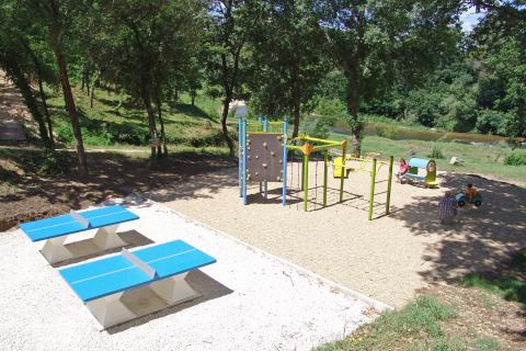 Parque infantil con juegos, mesas de ping pong y vegetación en Slow Village Provence Occitane, Francia.