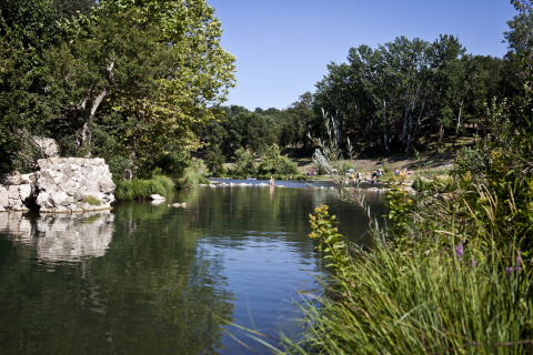 Rivier en grasvelden bij Slow Village Provence Occitane, Occitanië, Frankrijk met ontspannen bezoekers.