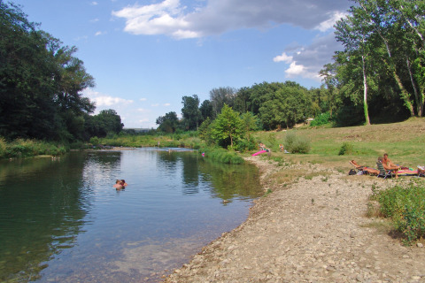 Personas relajándose junto al río en Slow Village Provence Occitane, parque vacacional en Occitania, Francia.