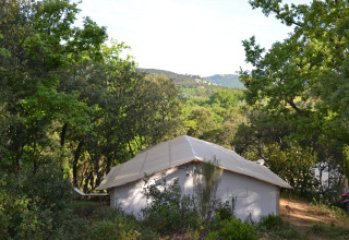 Hut met zeildoek dak omgeven door bomen en heuvels in Slow Village Provence Occitane, Occitanië, Frankrijk.
