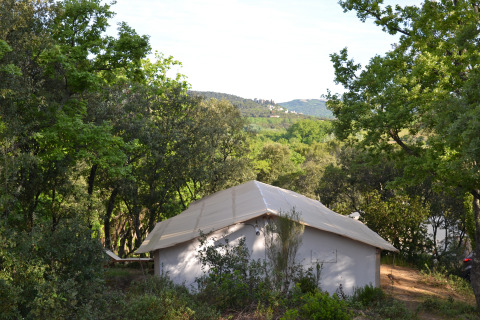 Cabane au toit en toile entourée d’arbres et collines à Slow Village Provence Occitane, Occitanie, France.