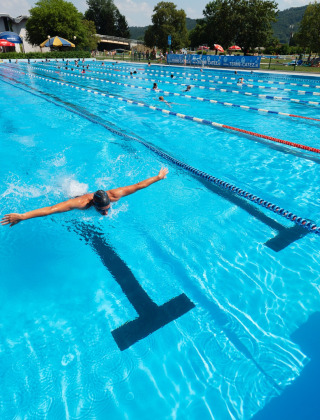 Piscina exterior en Camping Terme Catez, Eslovenia, con nadadores disfrutando bajo el sol de verano.