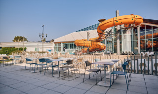 Zona de mesas al aire libre y gran tobogán naranja en Camping Terme Catez, parque de vacaciones en Eslovenia.