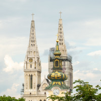 Dos agujas de catedral góticas y una torre de reloj entre vegetación cerca de Čatež ob Savi, Eslovenia.