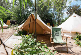 Glampingplaats bij RØSTIG vakantiepark in Utrecht, Nederland, met tenten en een stoel tussen het groen.