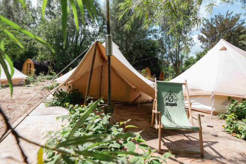 Glamping campsite at RØSTIG holiday park in Utrecht, Netherlands, with canvas tents and a chair outdoors.