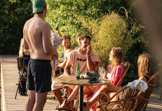 Jongeren genieten samen buiten aan een tafel in vakantiepark RØSTIG in Utrecht, Nederland.