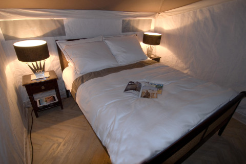Cama cómoda con sábanas blancas y mesillas de noche en una tienda safari en RoyalLodge, Slow Village Provence Occitane, Francia.