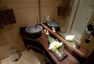 Baño elegante con lavabo moderno y flores en la tienda safari RoyalLodge, Slow Village Provence, Francia.